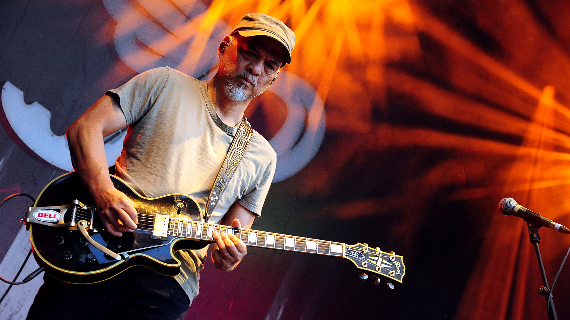 Joey Santiago spielt Gitarre bei einem Pixies-Konzert in Berlin im orangefarbenen Bühnenlicht