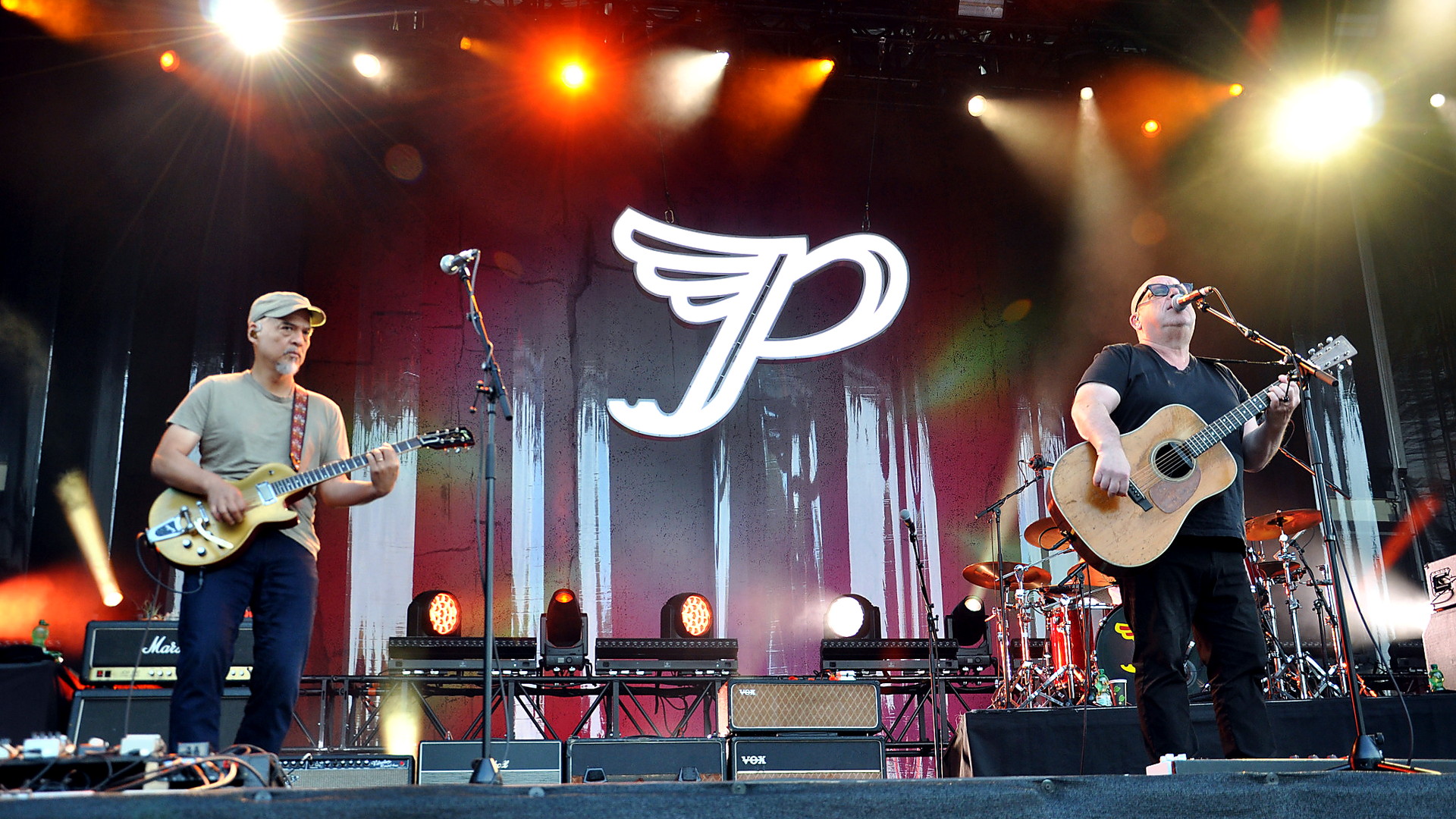 Black Francis und Joey Santiago von den Pixies bei einem Live-Konzert in Berlin vor dem beleuchteten Bandlogo