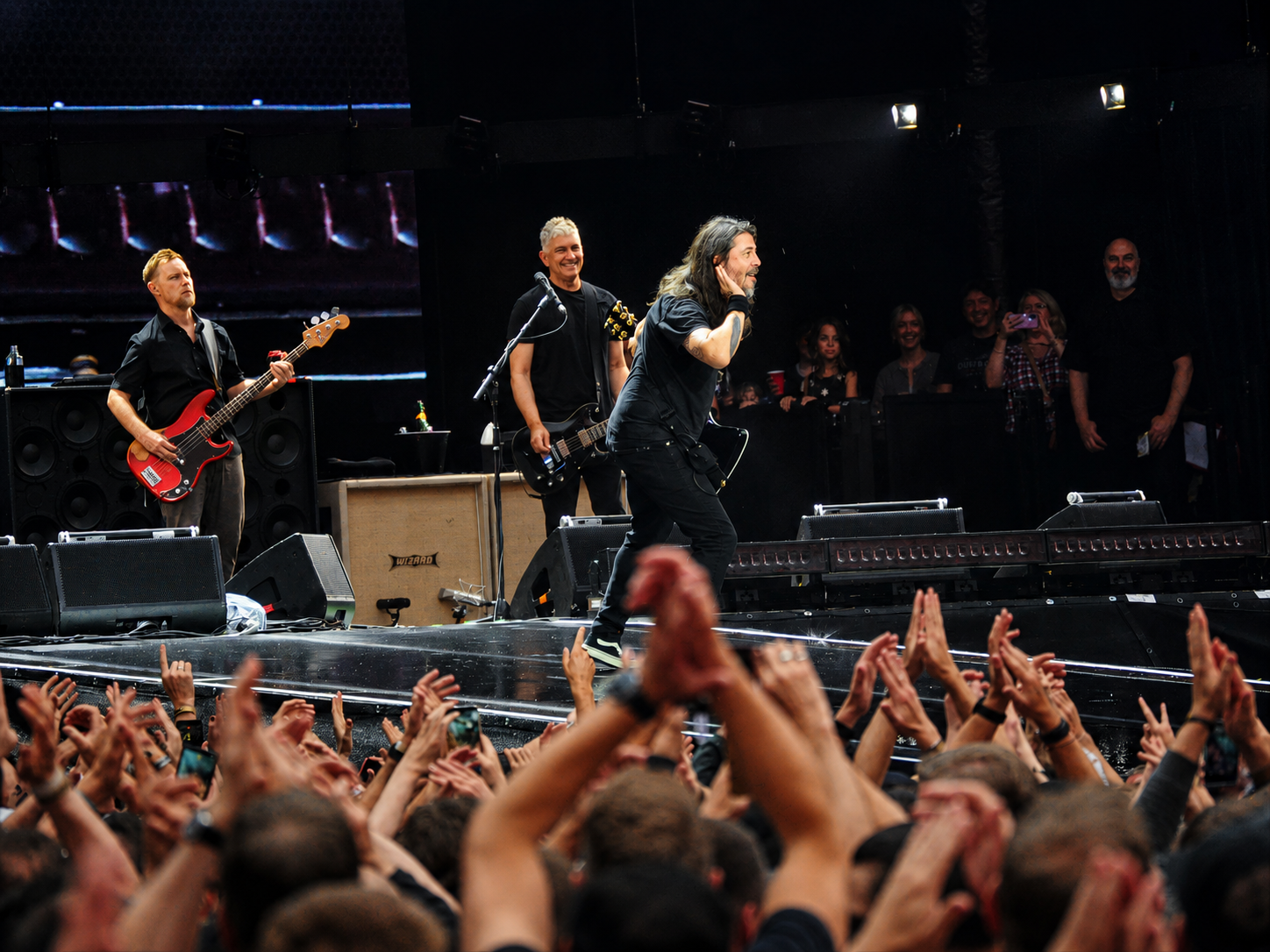 Der Sänger der Foo Fighters hält eine Hand ans Ohr und fordert die Fans im Olympiastadion Berlin zum Mitsingen auf.