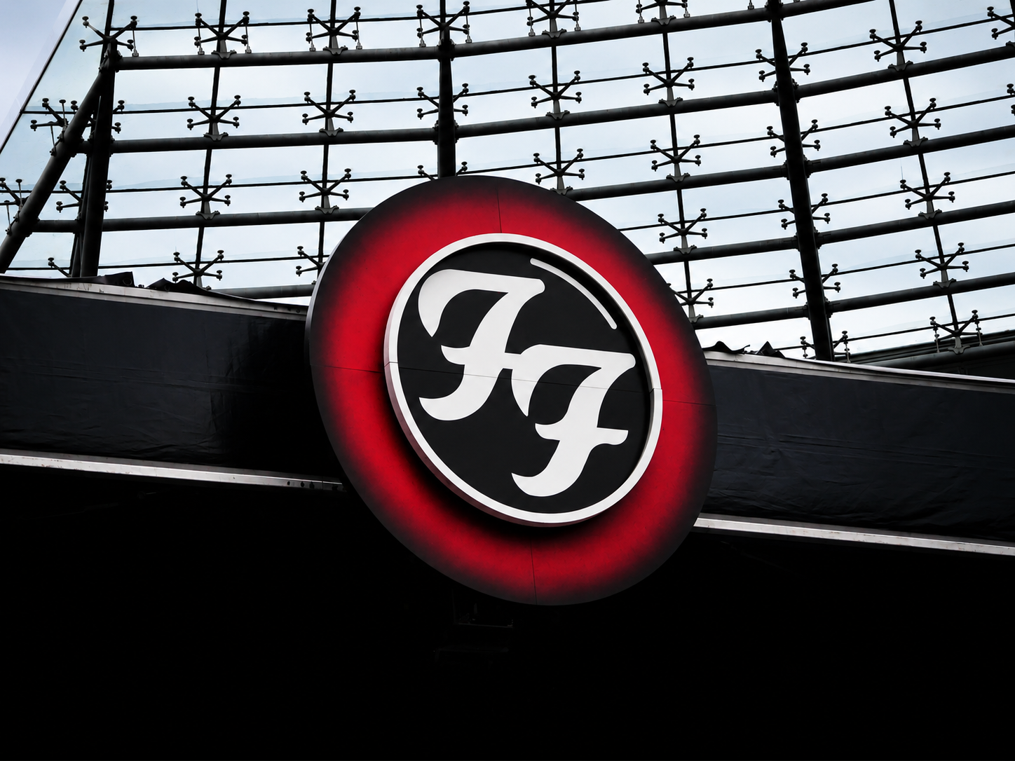 Beleuchtetes Foo-Fighters-Logo vor der markanten Dachkonstruktion des Berliner Olympiastadions.