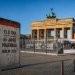 KI-generierte Illustration zu 65 Jahre Mauerbau Berlin 2026 mit Brandenburger Tor, Mauer-Element und Ausstellung zur deutschen Teilung