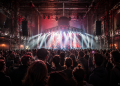 Pop-Kultur Berlin 2026 – volle Konzerthalle mit Publikum und rotem Bühnenlicht, KI-generierte Illustration