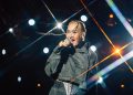 Sarah Connor singt bei einem Konzert auf der Bühne vor farbigen Lichtstrahlen