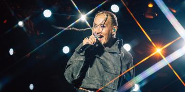 Sarah Connor singt bei einem Konzert auf der Bühne vor farbigen Lichtstrahlen