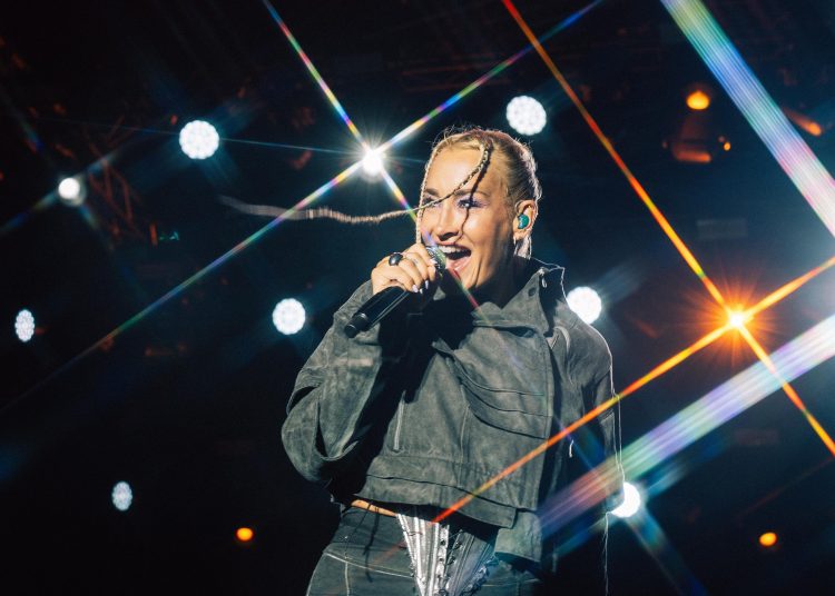 Sarah Connor singt bei einem Konzert auf der Bühne vor farbigen Lichtstrahlen