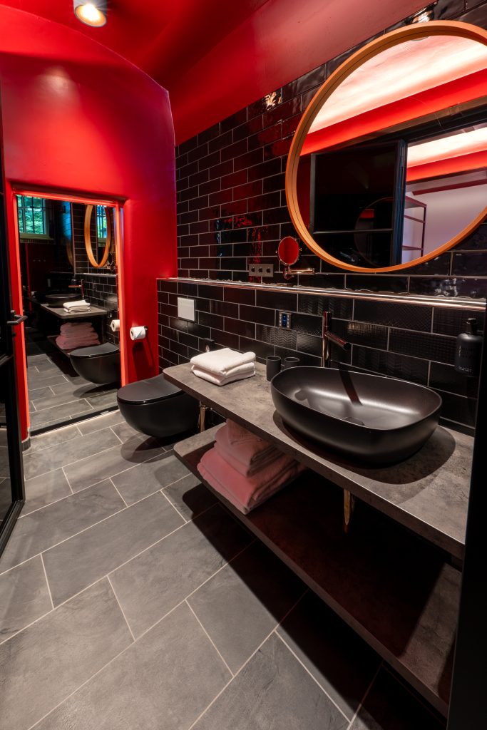 Zellenzimmer im THE KNAST Hotel Berlin-Lichterfelde mit Doppelbett und weinrotem Interior