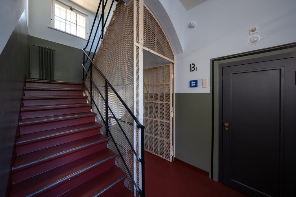 Zellenzimmer im THE KNAST Hotel Berlin-Lichterfelde mit Doppelbett und weinrotem Interior