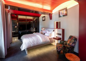 Zellenzimmer im THE KNAST Hotel Berlin-Lichterfelde mit Doppelbett und weinrotem Interior
