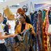 Zwei Frauen betrachten farbenfrohe Kleidung und handgefertigte Textilien an einem Verkaufsstand auf dem Bazaar Berlin.