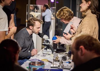 Besucher entdecken bei der Berlin Science Week wissenschaftliche Experimente an einem Mikroskop und tauschen sich mit Forschern aus.