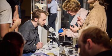 Besucher entdecken bei der Berlin Science Week wissenschaftliche Experimente an einem Mikroskop und tauschen sich mit Forschern aus.