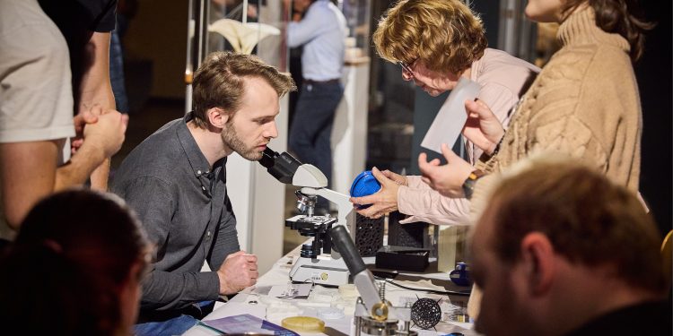 Besucher entdecken bei der Berlin Science Week wissenschaftliche Experimente an einem Mikroskop und tauschen sich mit Forschern aus.