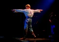 David Bowie steht mit ausgestreckten Armen auf einer dunkel beleuchteten Konzertbühne – Pressefoto zur Show STAGE in Berlin 2027