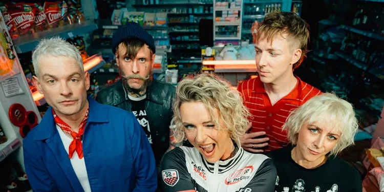 Jennifer Rostock auf einem aktuellen Bandfoto von 2026: Die fünf Musiker stehen gemeinsam in einem Kiosk. Am 8. Mai 2027 spielt die Band im Velodrom Berlin.