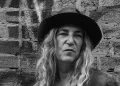Patti Smith mit Hut und langen Haaren vor einer Backsteinwand – Porträt der Rockmusikerin, die 2027 in der Zitadelle Spandau auftritt