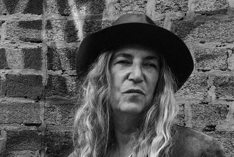 Patti Smith mit Hut und langen Haaren vor einer Backsteinwand – Porträt der Rockmusikerin, die 2027 in der Zitadelle Spandau auftritt