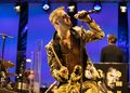 Philipp Hochmair mit Mikrofon, Sonnenbrille und goldener Jacke bei „Jedermann Reloaded“ auf der Bühne.