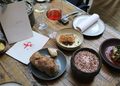 Kreative Sharing-Gerichte, Wein und die Speisekarte des QUI31 auf einem gedeckten Restauranttisch in Berlin-Charlottenburg.